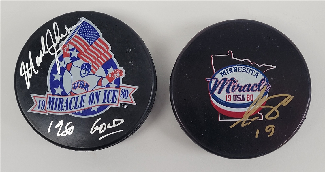 Lot of 2 Mark Johnson & Eric Strobel Autographed 1980 Olympic Hockey Pucks